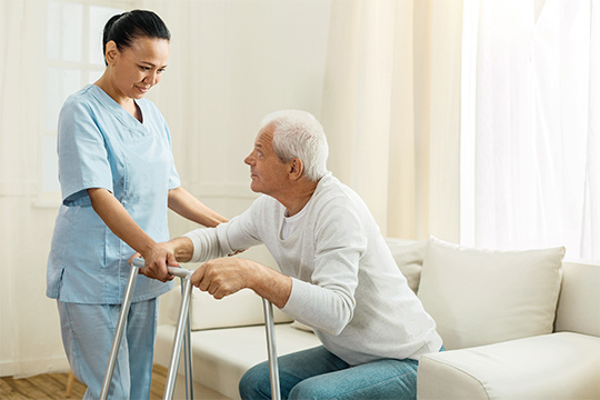 woman-working-as-a-caregiver-helping-senior-man-stand